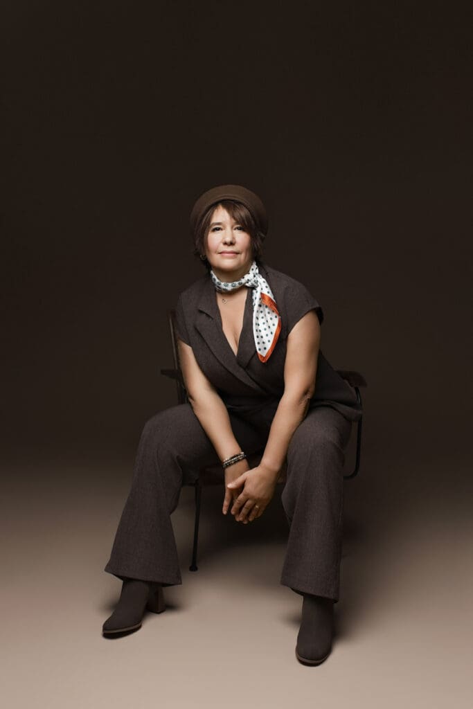 Portrait de femme assise avec béret et foulard pendant une séance photo portrait femme en studio.