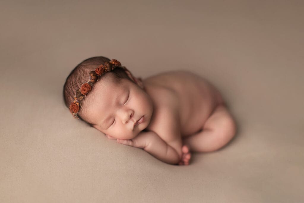 nouveau-né endormi avec bandeau fleuri – photo naissance douce en studio en Seine-et-Marne