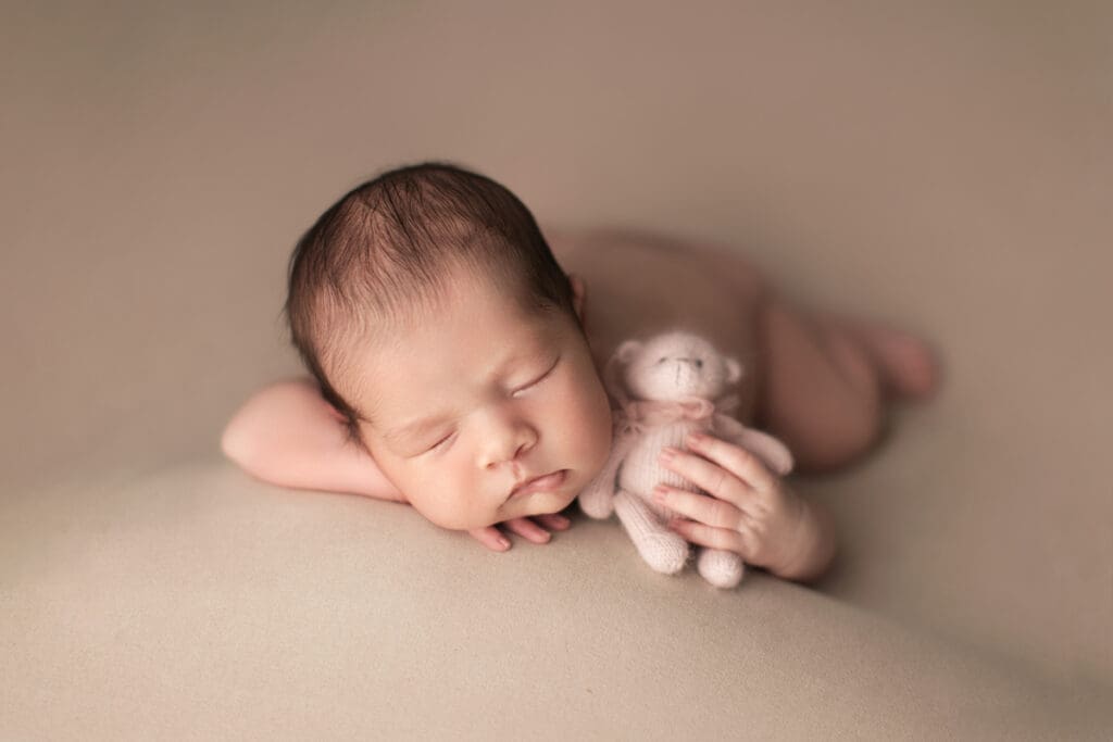 bébé endormi tenant un petit ours – séance photo nouveau-né en studio à Lognes