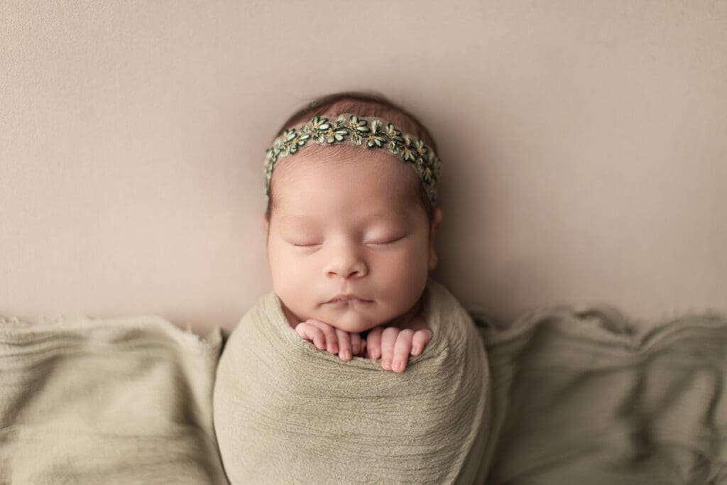 portrait de bébé emmailloté avec bandeau vert – séance photo nouveau-né en studio

9️⃣