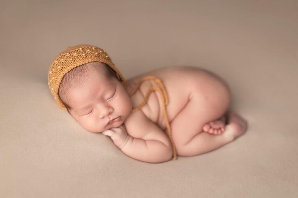 bébé nouveau-né endormi avec bonnet moutarde – séance photo naissance en studio à Lognes en Seine-et-Marne